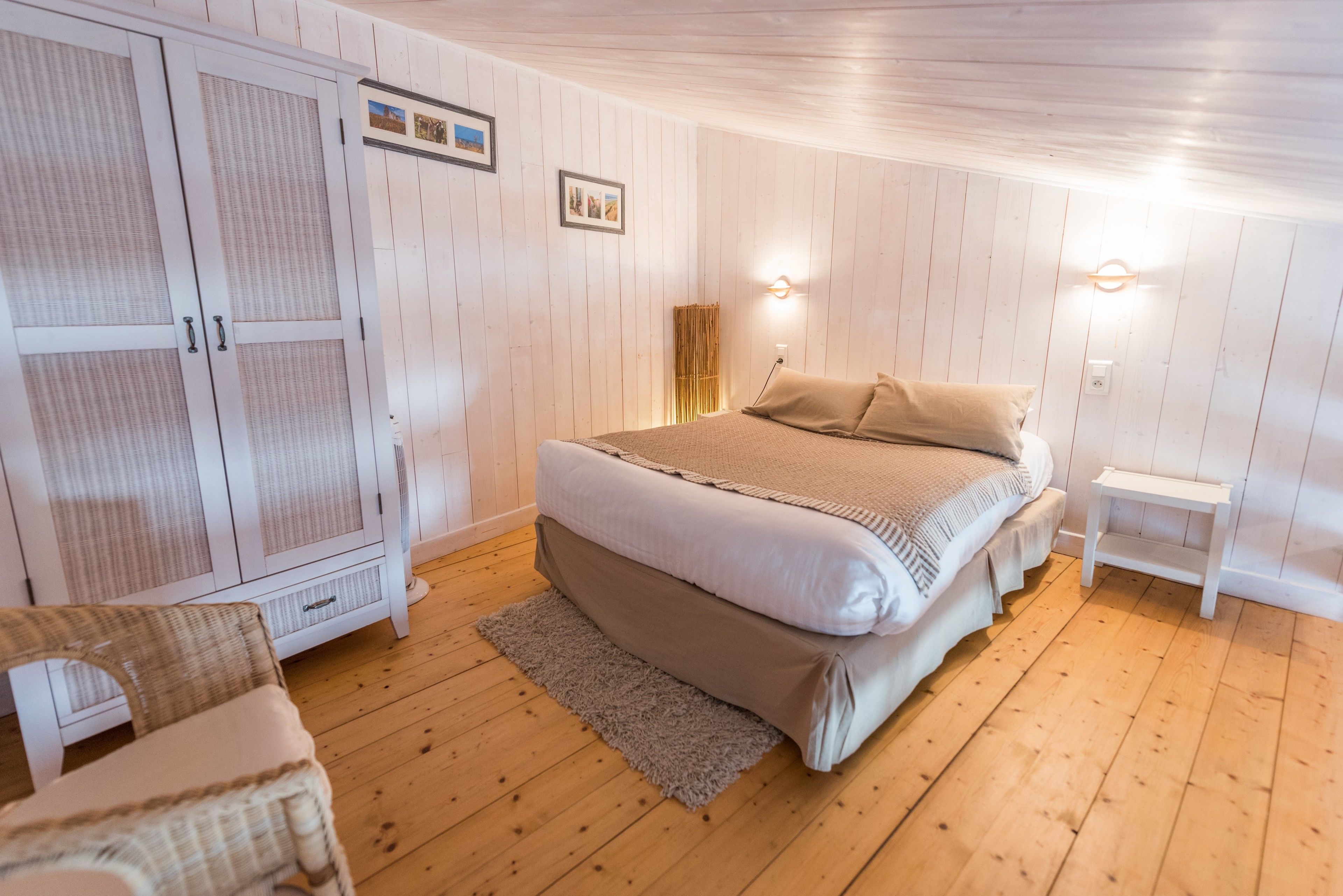 Quarto com cama, guarda-roupa, mesa de cabeceira e uma cadeira.