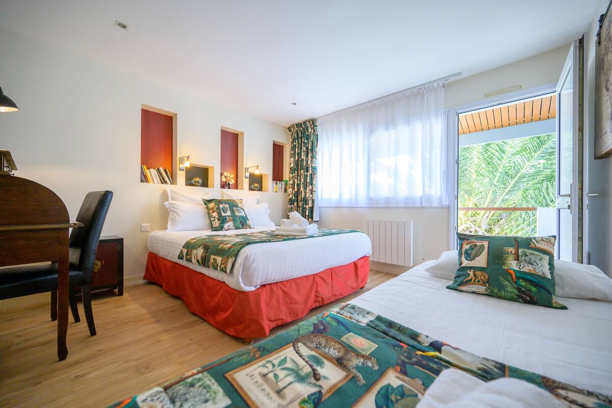 Un dormitorio con cama, una silla, un escritorio y ventana con vista a zonas verdes.