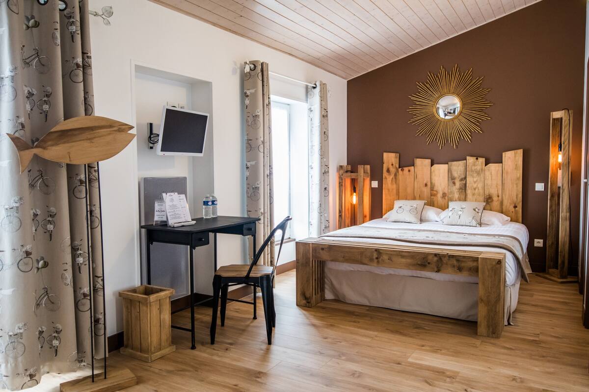 Un dormitorio con una cama de madera, un escritorio con una silla, un televisor y un espejo en la pared.