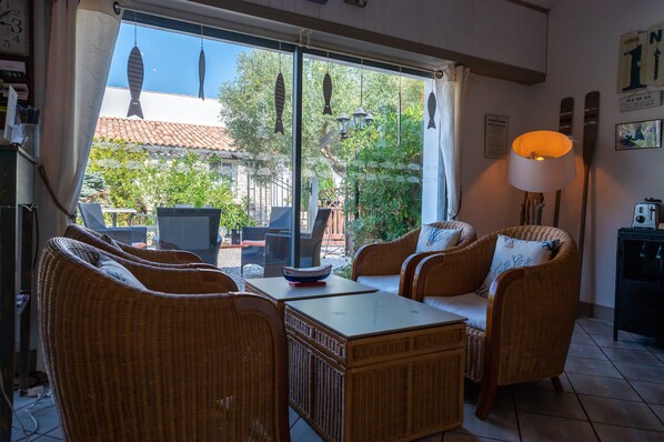 A cozy room with wicker furniture, a table, and a view of the outdoors.