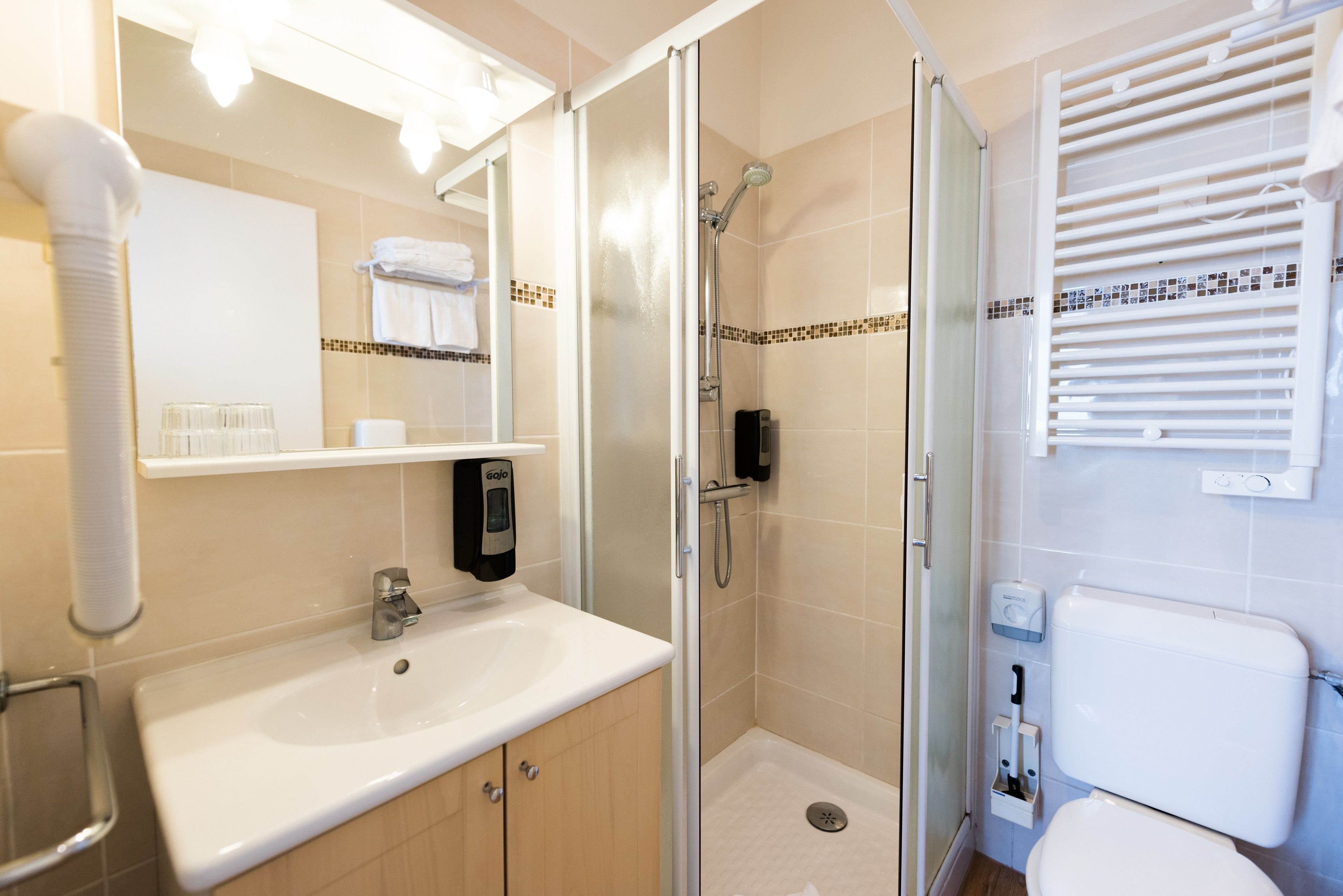 Un baño moderno con ducha de vidrio, lavamanos blanco y un inodoro.