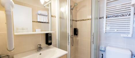Un baño moderno con ducha de vidrio, lavamanos blanco y un inodoro.