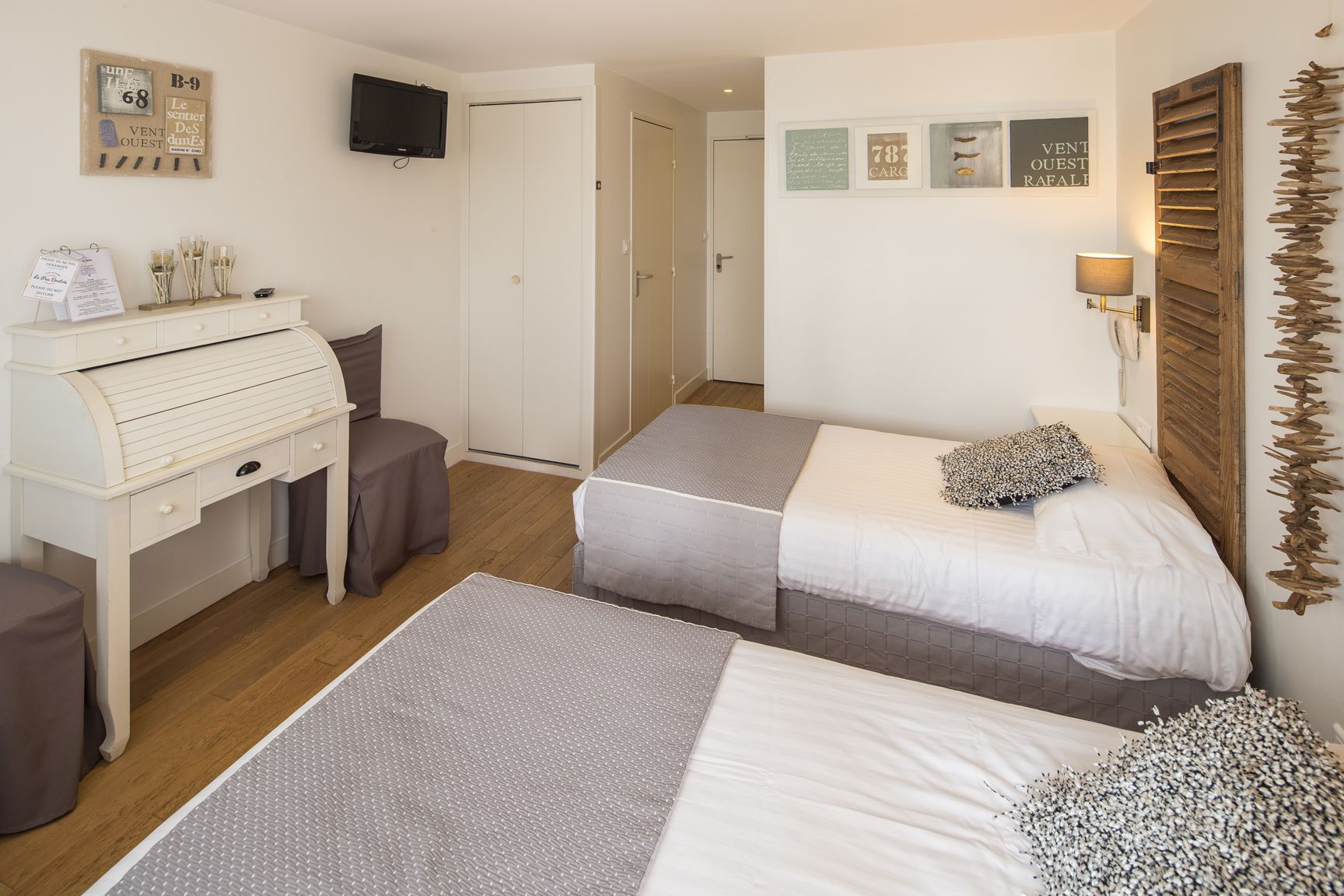Una camera da letto con due letti, una scrivania, una sedia, una televisione e una porta.