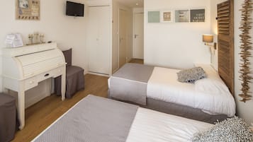Una camera da letto con due letti, una scrivania, una sedia, una televisione e una porta.