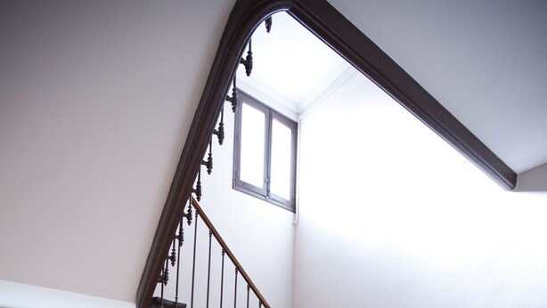 Una escalera de madera con barandilla metálica que conduce a un piso superior.