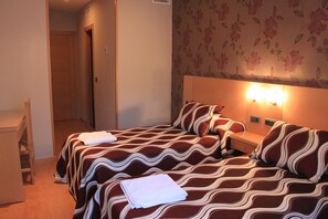 A hotel room with two beds, a wooden nightstand, a lamp, and a floral wallpaper. - Jemasaca Palma 61 (Madrid)