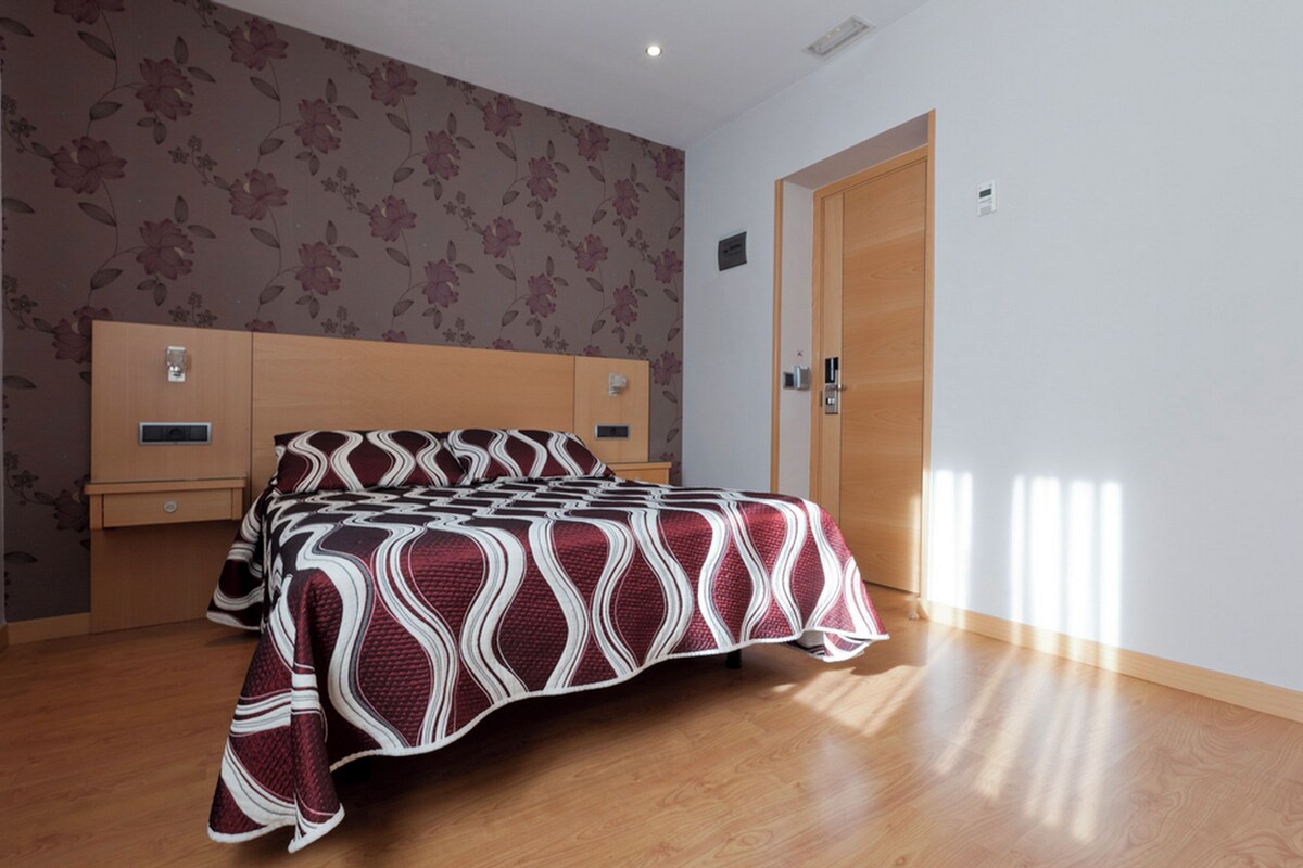 A bedroom with a wooden bed, a nightstand, a wardrobe, and a door.