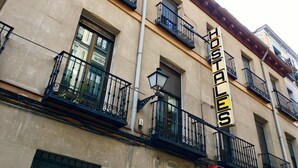 Un edificio con varios balcones, un letrero que dice "Hostales" y una ventana que ofrece vistas de otro edificio.