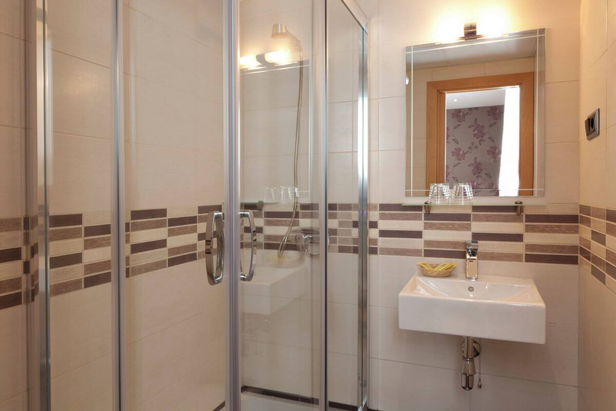 Un baño moderno con cabina de ducha de vidrio, un lavabo blanco y un espejo encima.