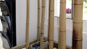 A bamboo water feature with rocks and pebbles, located in a corner of a room with a window and a door. - Hostal Pensió Maricel (Sitges)