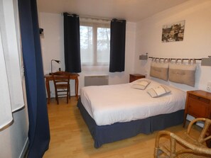 A bedroom with a bed, a desk, a chair, a nightstand, and a wall-mounted lamp. - Auberge Saint Martin (Surville)