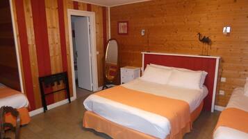 A hotel room with a wooden wall, a bed with white and orange bedding, a chair, and a small table with a mirror.