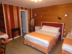 A hotel room with a wooden wall, a bed with white and orange bedding, a chair, and a small table with a mirror. - Auberge Saint Martin (Surville)