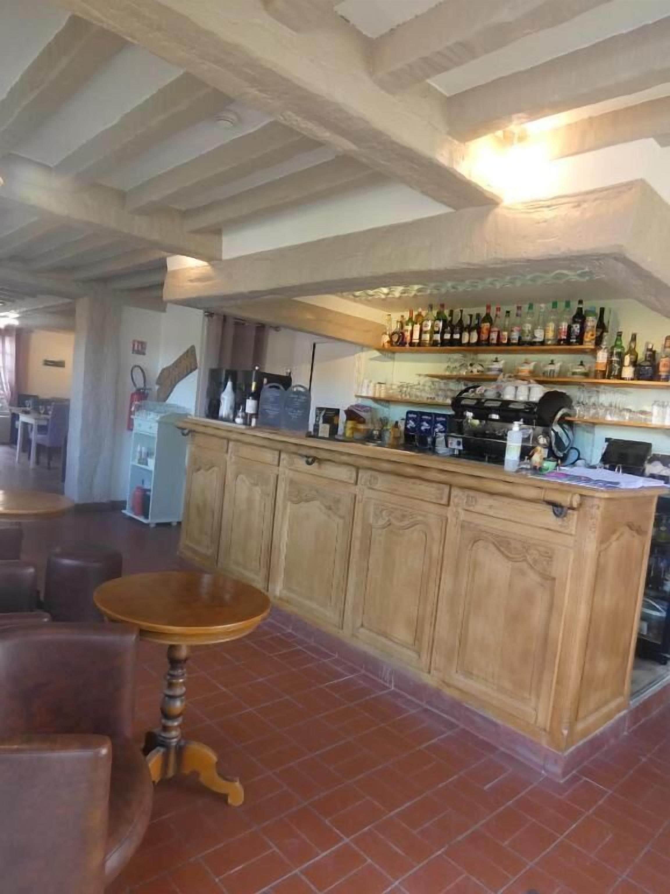 A bar area with wooden cabinets, a bar counter, and a seating area with a round table.