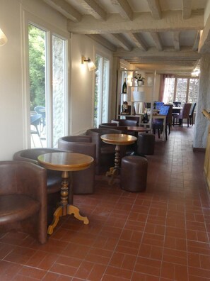 A restaurant with a long counter, multiple tables, and chairs. There are large windows on one side. - Auberge Saint Martin (Surville)