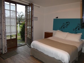 Un dormitorio con cama, mesita de noche, ventana con cortinas y un diseño floral en la pared.