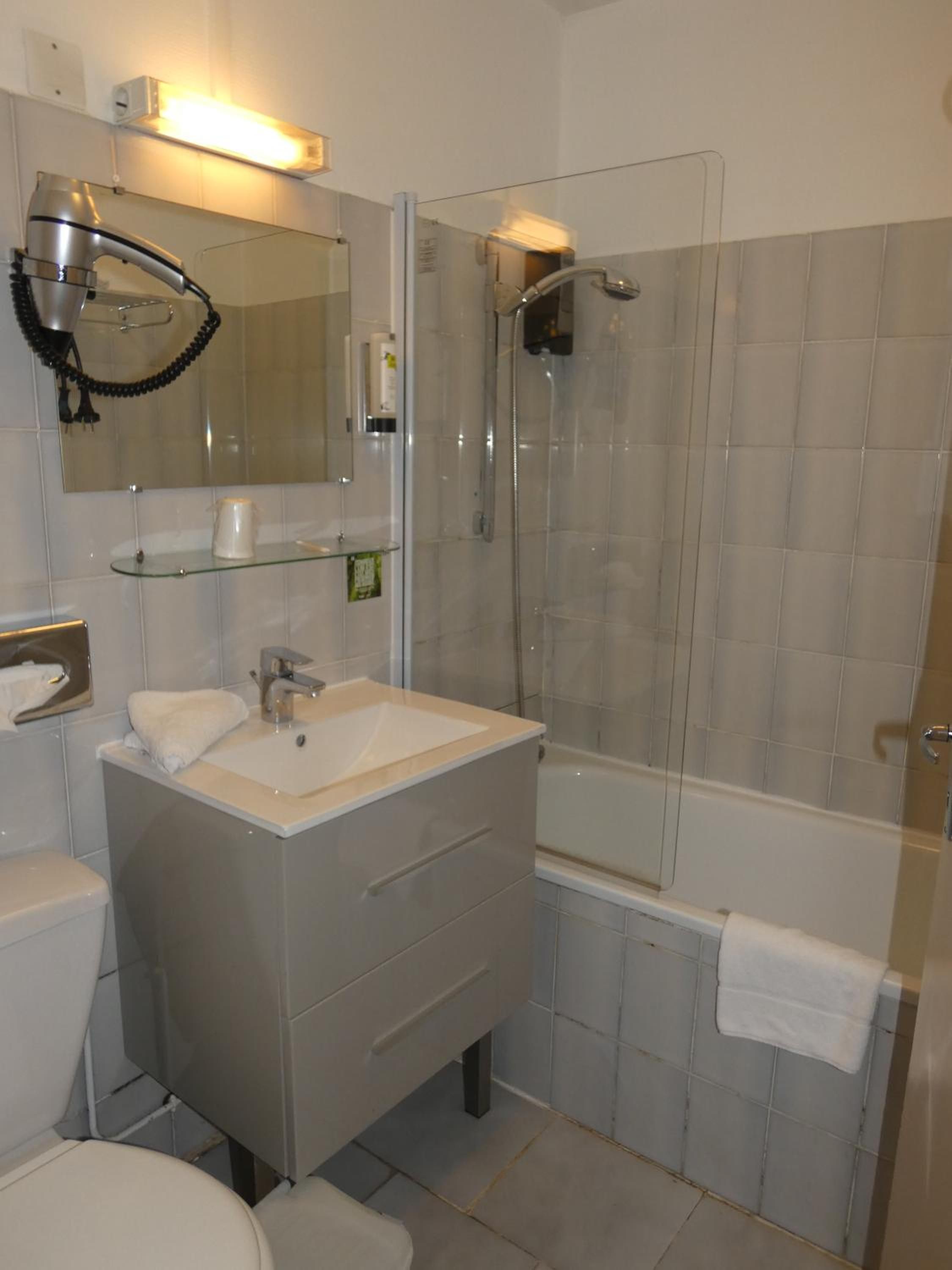 A modern bathroom with a glass shower enclosure, a white sink, and a toilet.