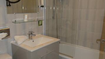 A modern bathroom with a glass shower enclosure, a white sink, and a toilet.