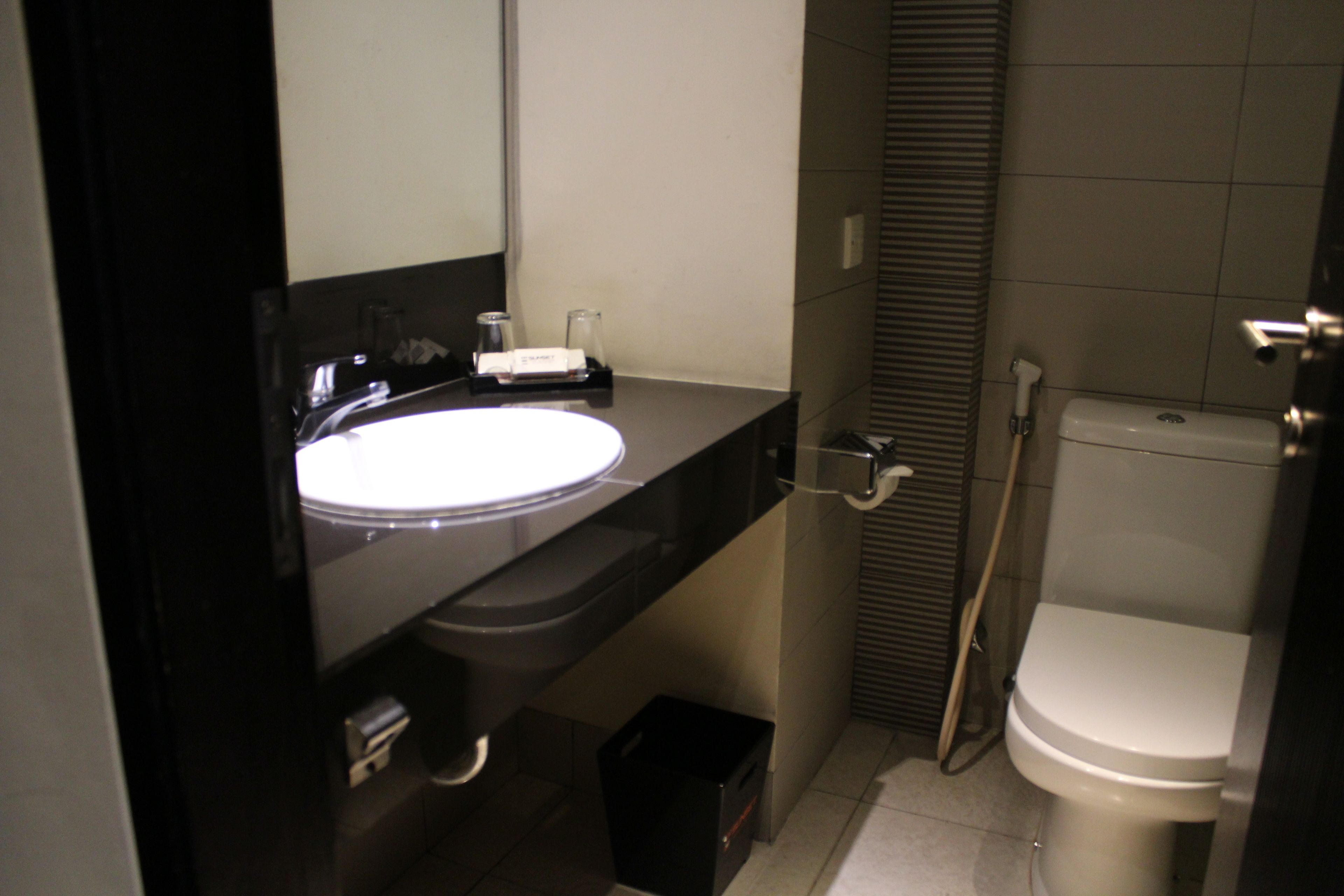 Une salle de bain avec un lavabo, un miroir et des toilettes noirs.
