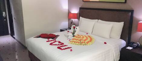 A hotel room with a neatly made bed, a bedside table with a lamp, and a painting on the wall.