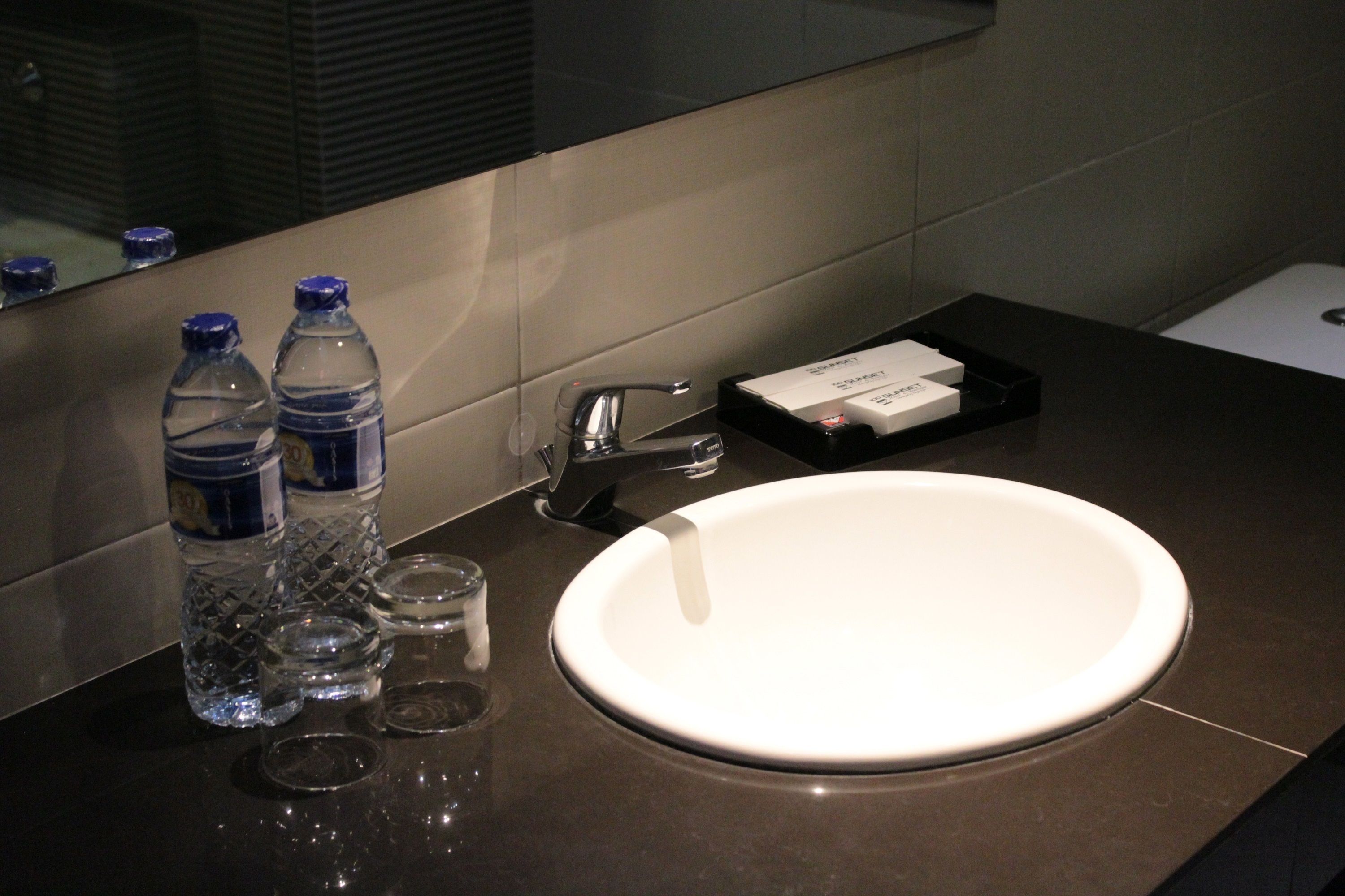 A bathroom with a white sink, a mirror, and two water bottles.