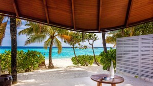 A covered outdoor seating area with a view of the beach and ocean.