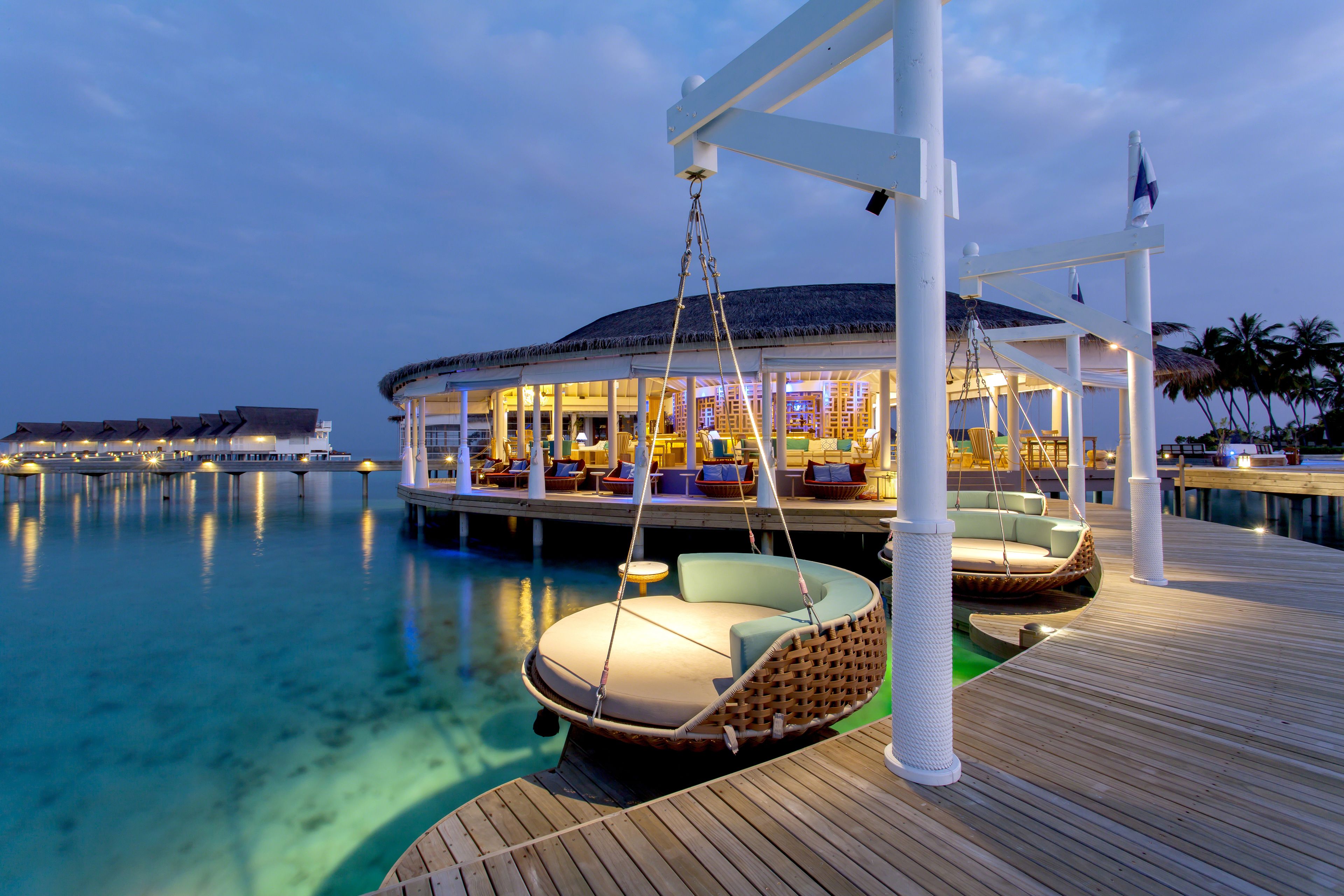A luxurious resort with a floating bar, overwater cabanas, and a pool.