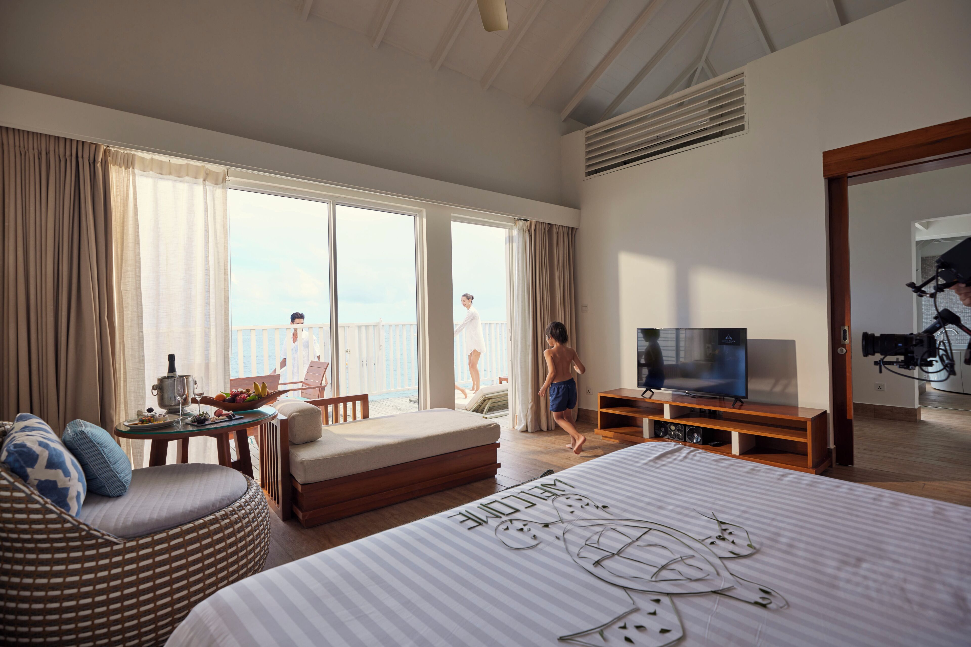 A hotel room with a large bed, a television, a balcony with a view, and a dining area.