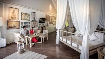 Una habitación con piso de madera, una mesa de comedor con sillas, una cama con dosel y varias fotos enmarcadas en las paredes.