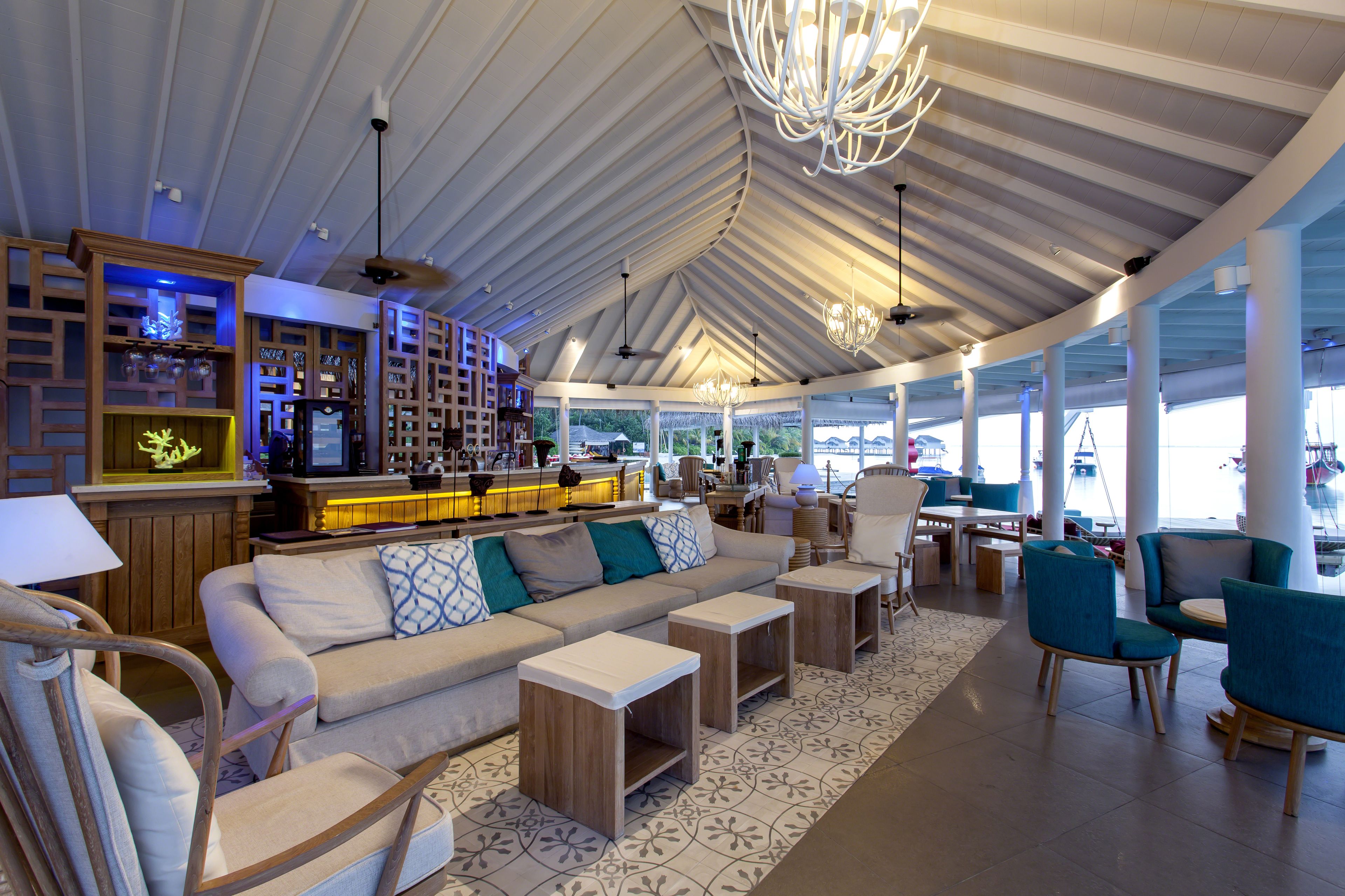 A spacious lounge area with a high ceiling, a bar, and comfortable seating.
