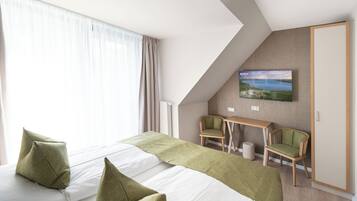 Une chambre d’hôtel avec deux lits, un bureau, deux chaises, une télévision et une vue sur un paysage.