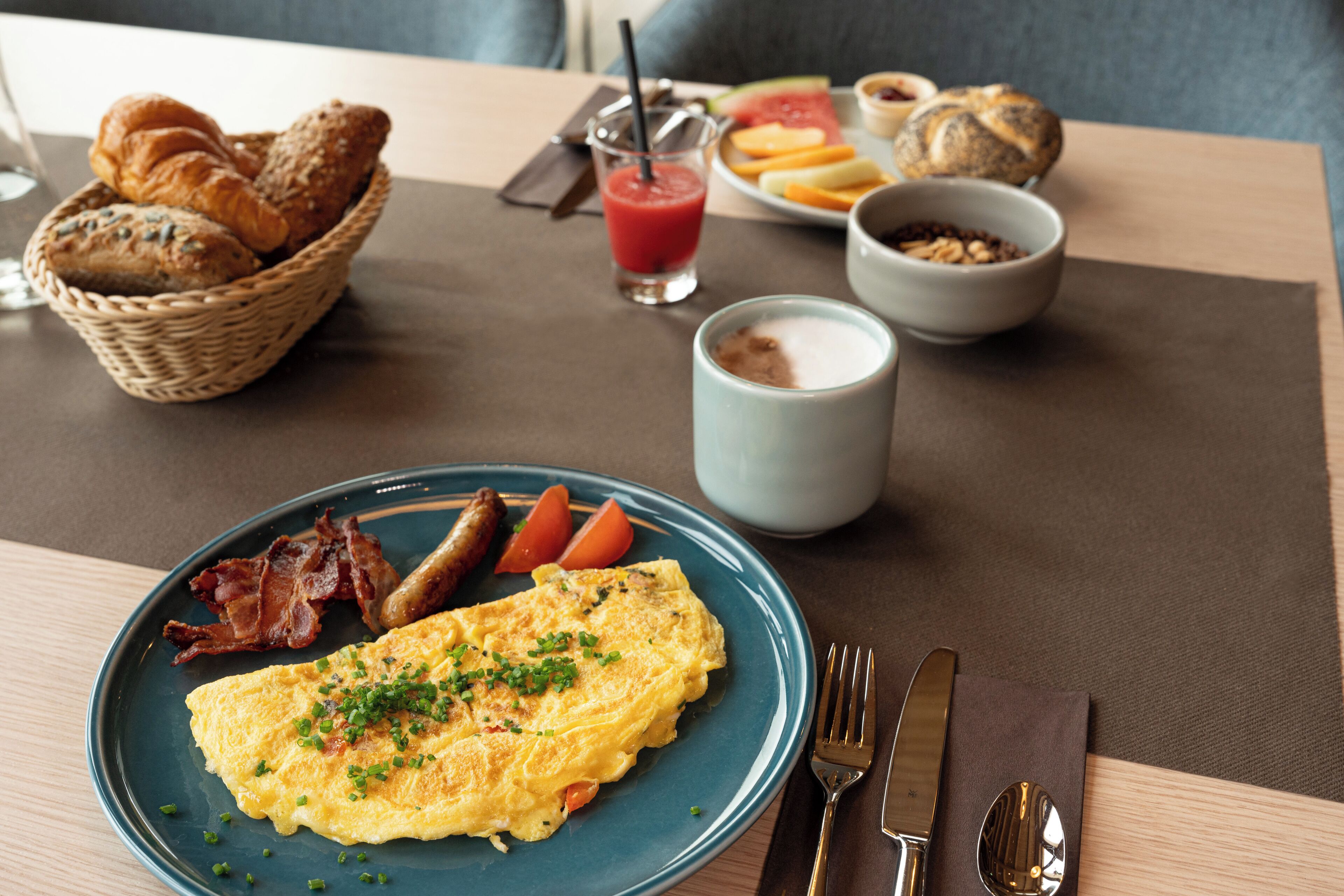 Breakfast items including eggs, bacon, toast, and a croissant basket on a table.