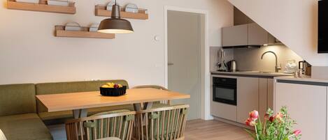 A modern kitchen with wooden cabinets, a dining table with chairs, and a built-in oven.