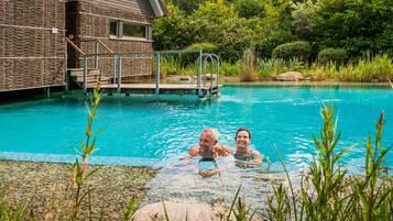 Una piscina con una parete in pietra e un pontile di legno.