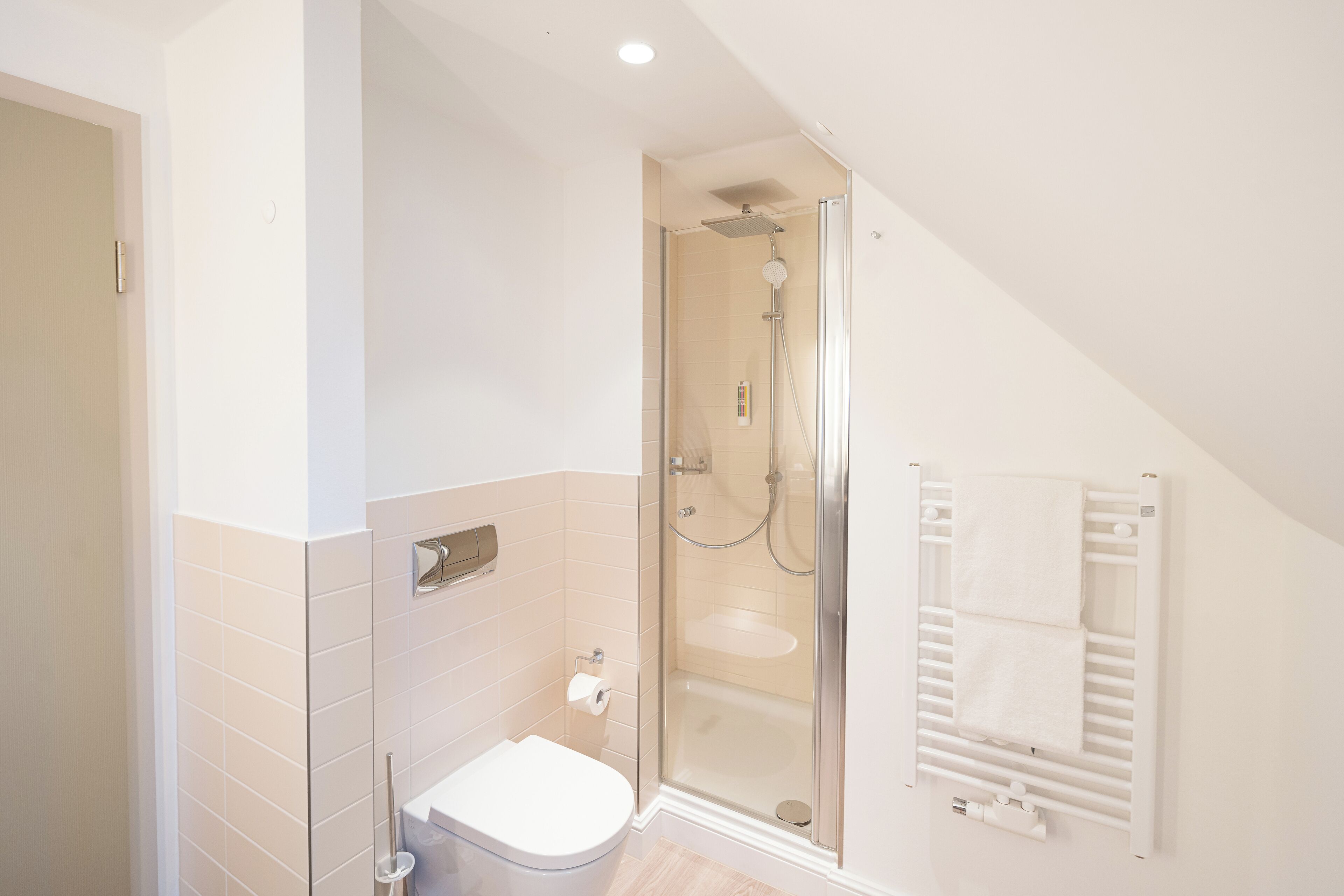 A modern bathroom with a glass-enclosed shower, a toilet, and a towel rack.