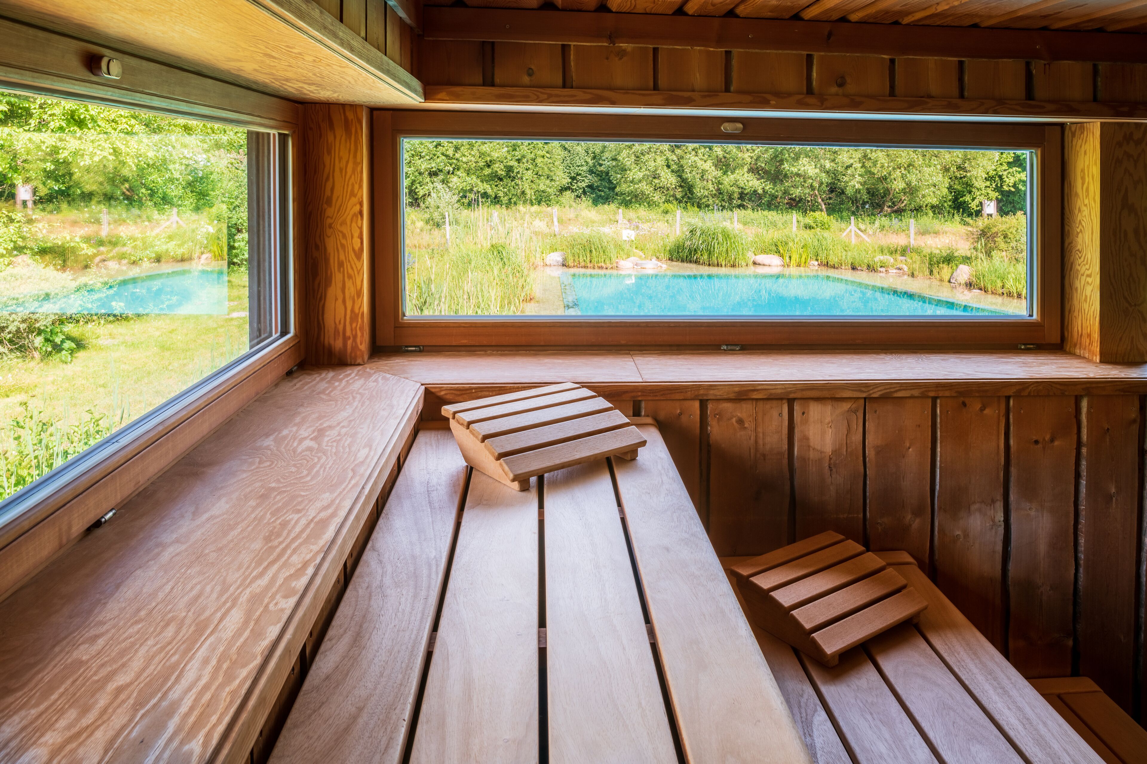 Un banc en bois offrant une vue sur une piscine et sur la verdure.