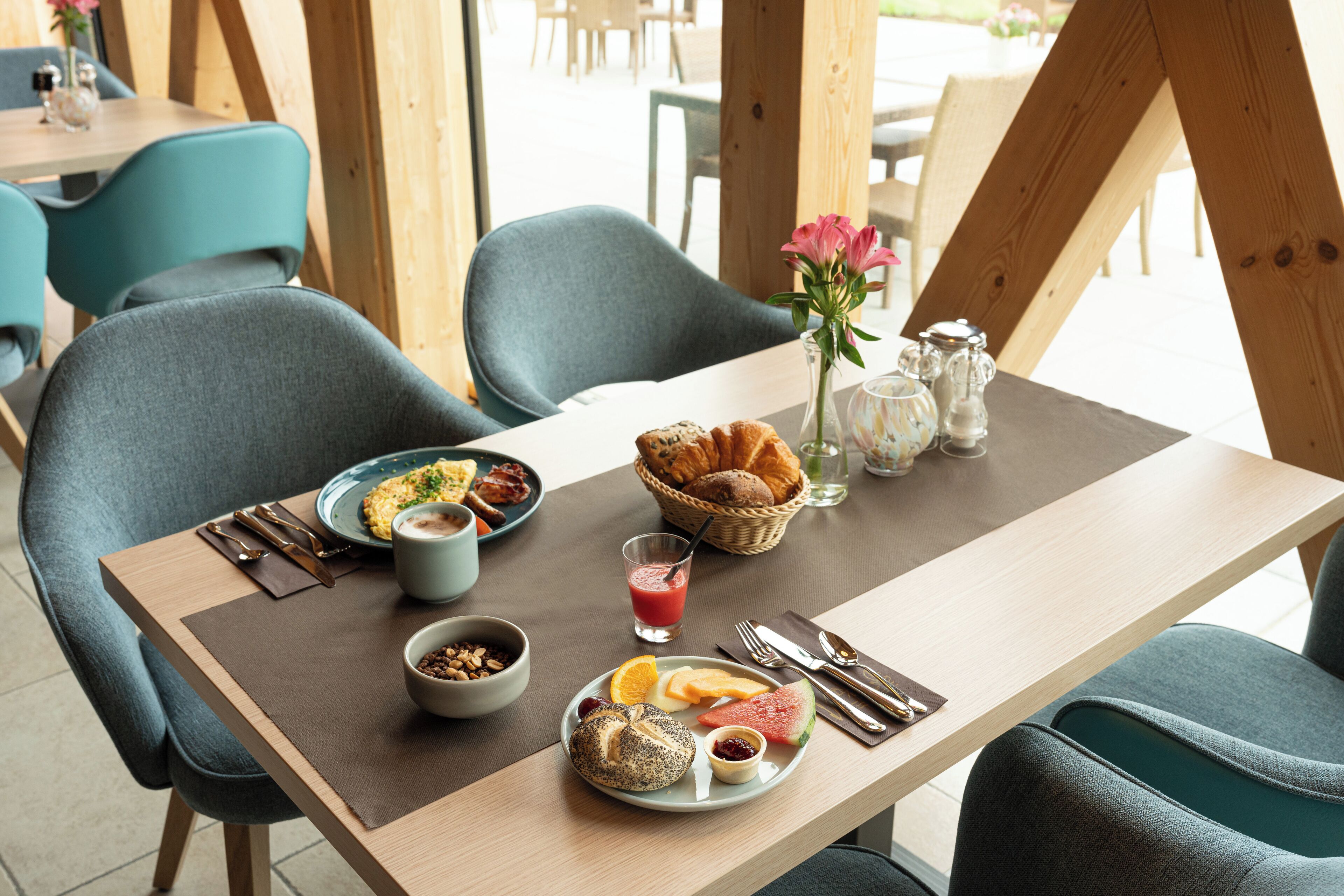 Una mesa de desayuno con croissants, un tazón de cereal, un vaso de jugo y un plato con fruta y un muffin.