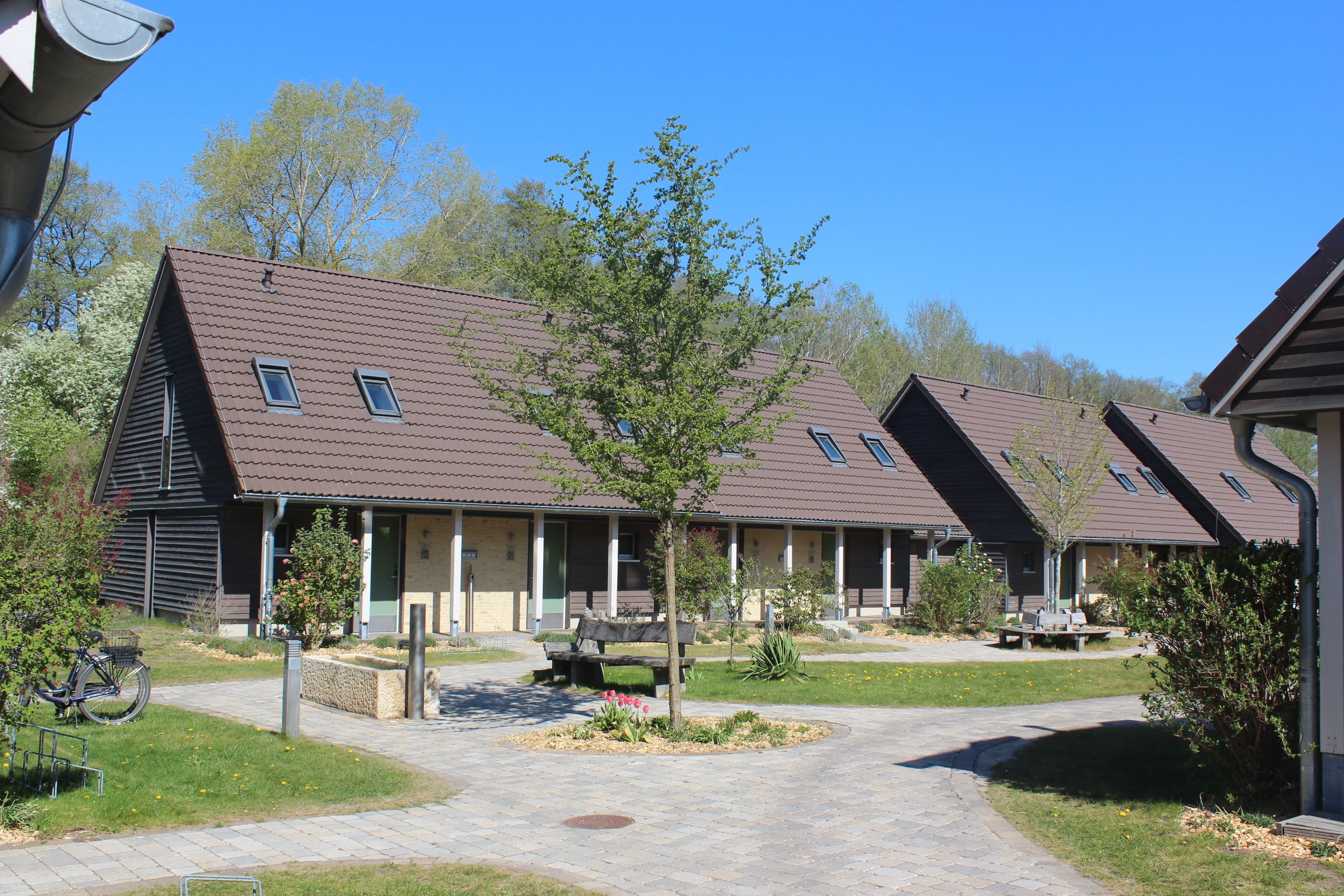 A row of single-story buildings with a central courtyard, each with a small window and a door.