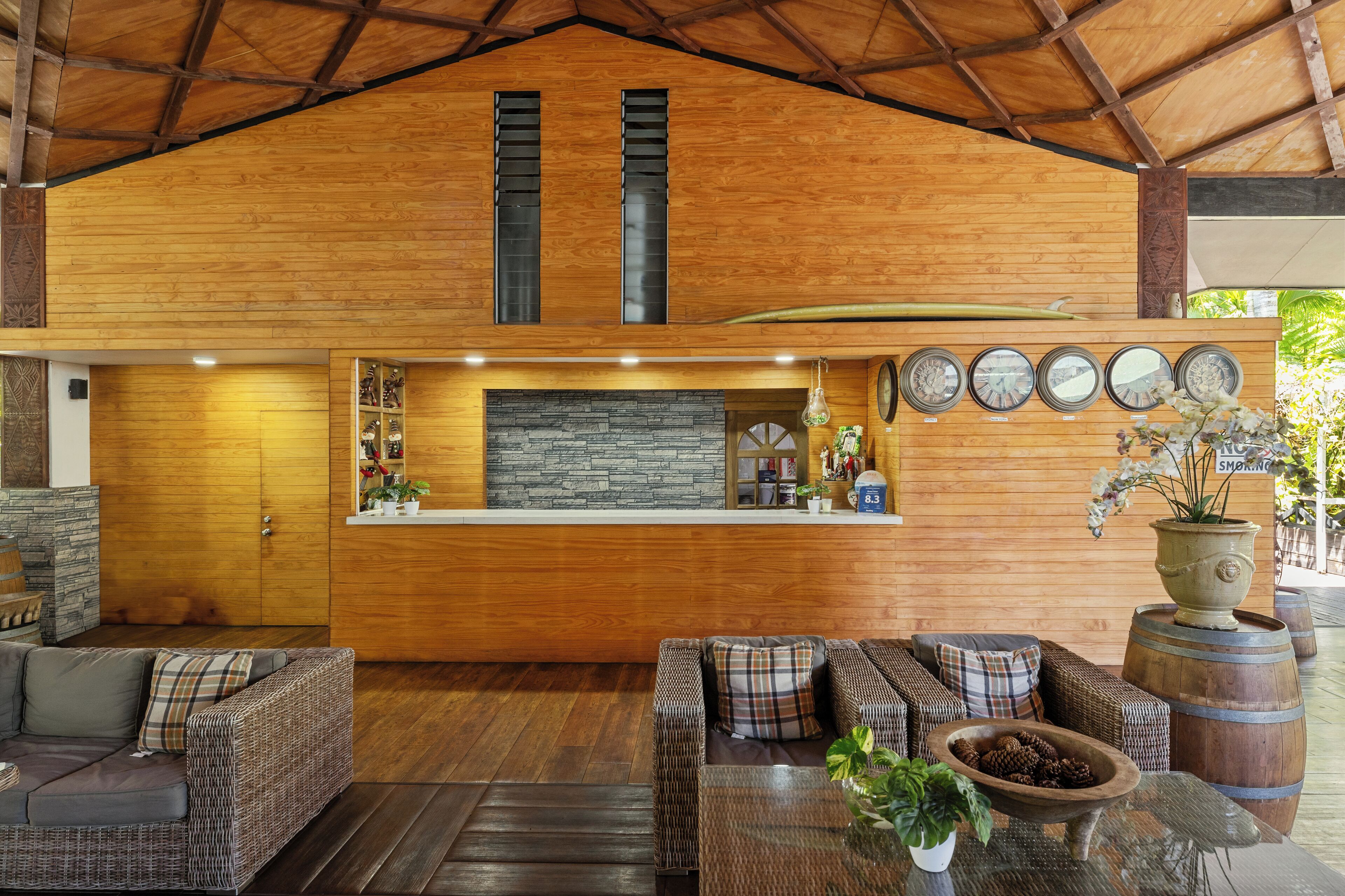 A wooden interior with a reception desk, wicker furniture, and a stone fireplace.