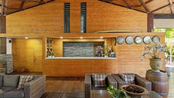 A wooden interior with a reception desk, wicker furniture, and a stone fireplace.