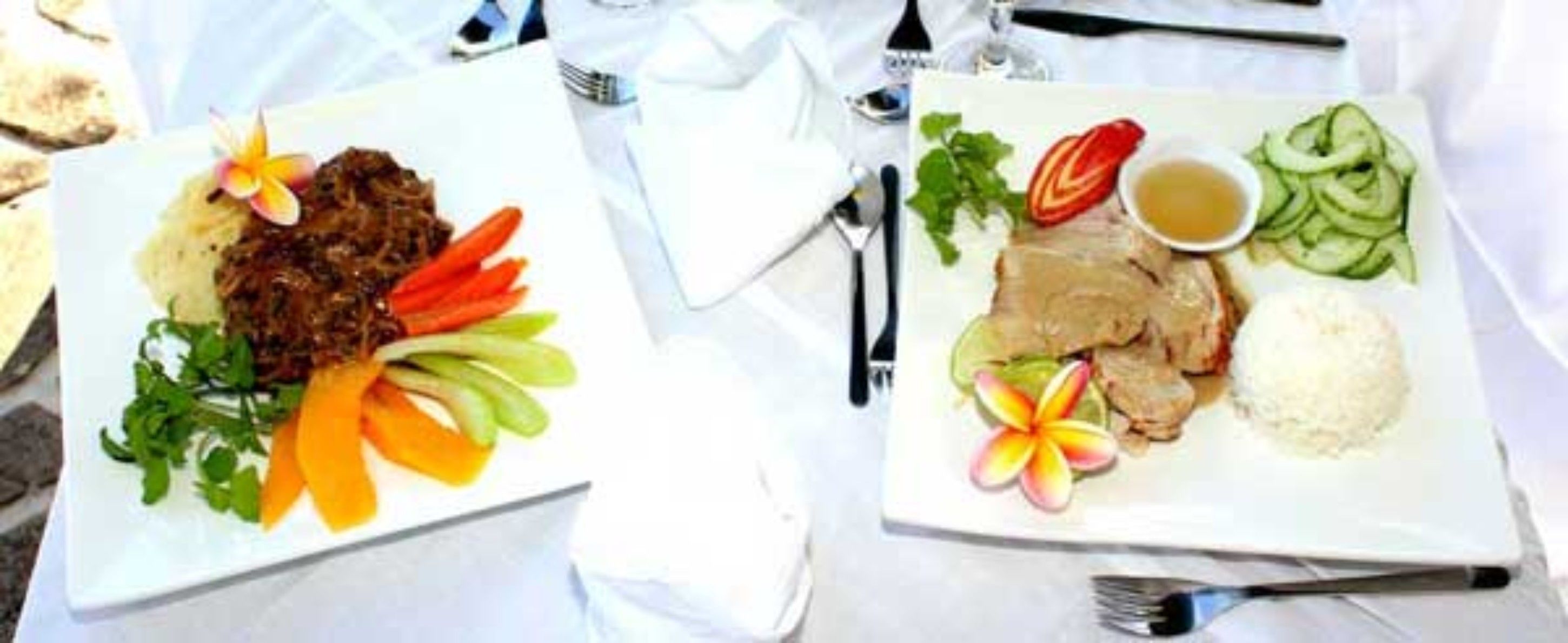 Two plates of food with a fork and knife on a table.