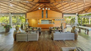 A spacious lobby with a high wooden ceiling, wicker furniture, and large potted plants. - Orator Hotel Samoa (Apia)
