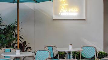 An outdoor seating area with wicker chairs and a neon sign.