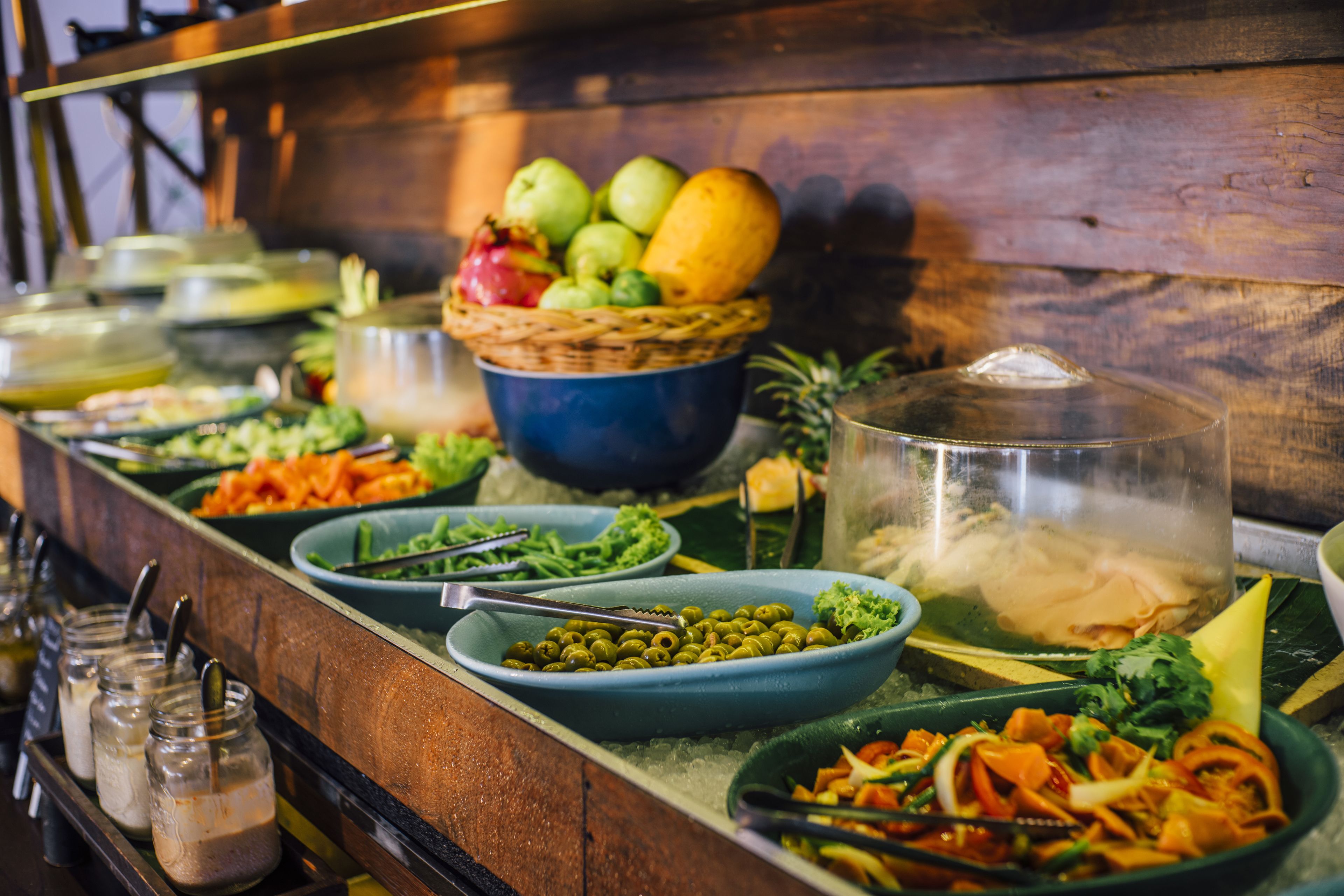 A buffet with various dishes and a fruit basket.
