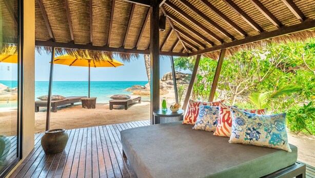 A wooden deck with a bed, a table, and an umbrella. - Buri Rasa Village Phangan (Ko Pha-ngan)