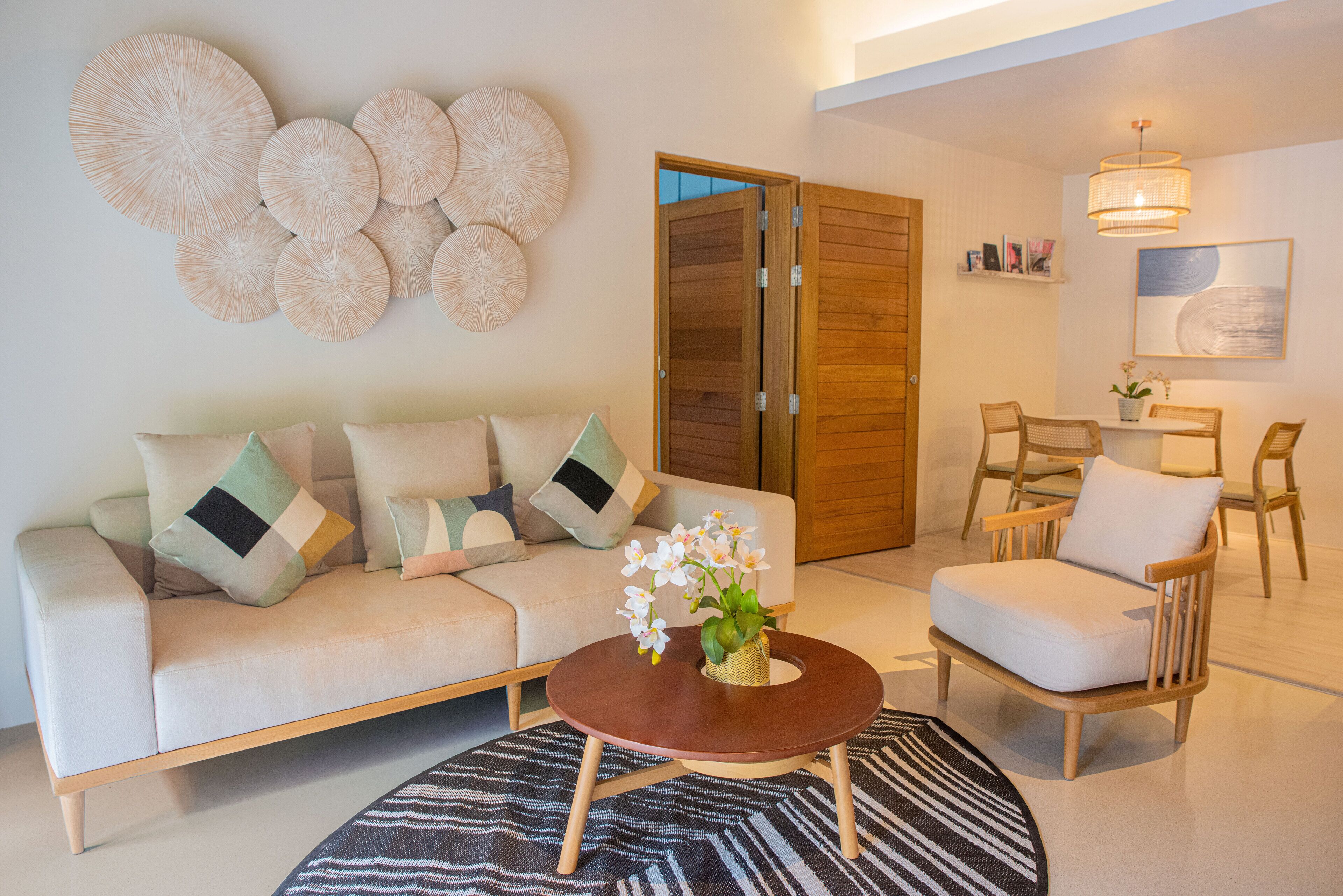 A modern living room with a sofa, armchairs, a coffee table, and a decorative wall piece.