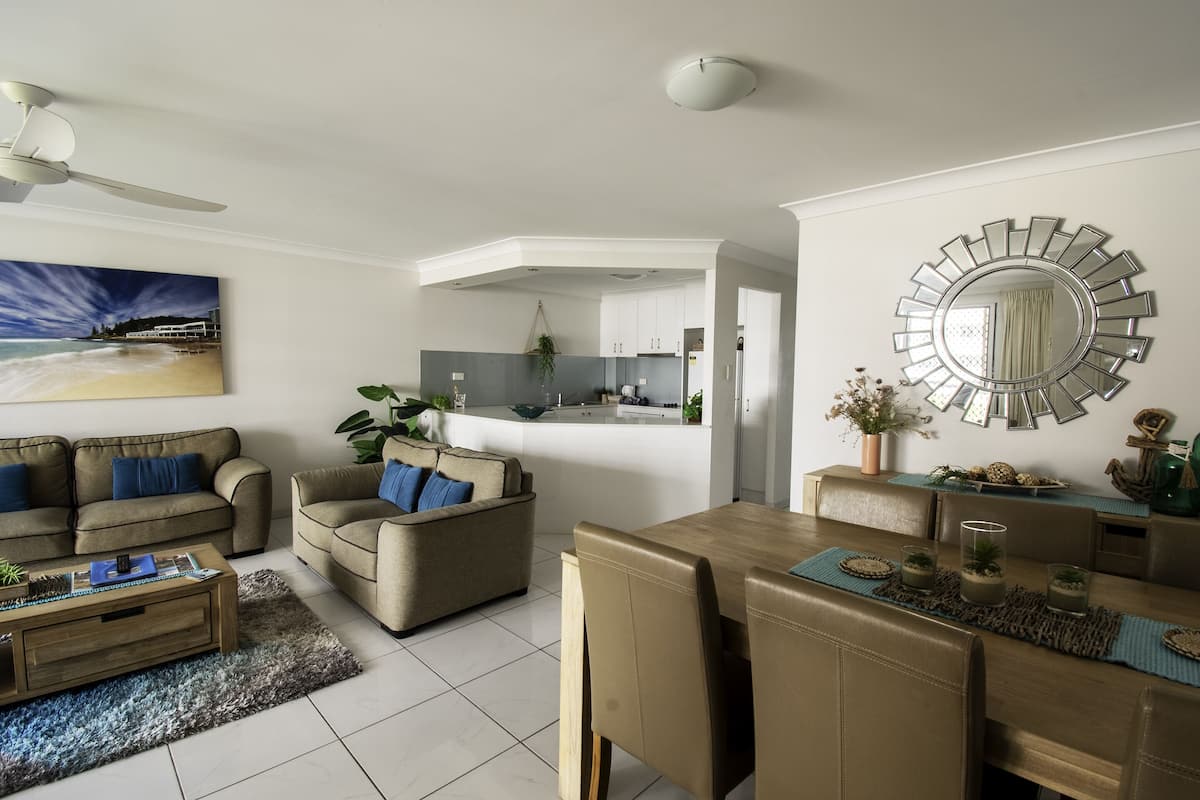 A modern living room with a sofa, coffee table, and dining area.