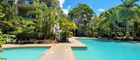 Una piscina al aire libre, sillones reclinables de piscina