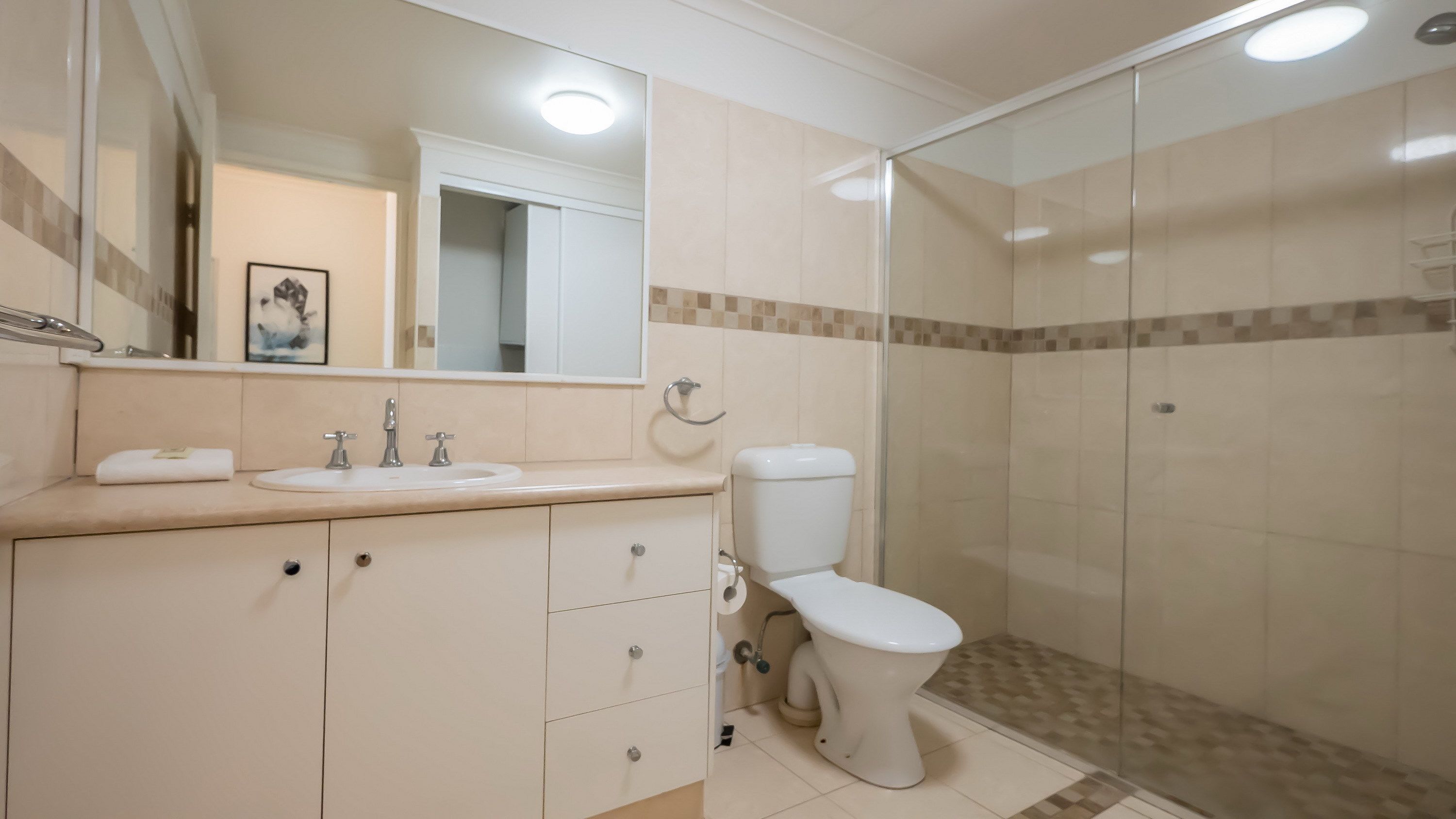 Een badkamer met een wastafel, spiegel, toilet en douchecabine met glazen wanden.