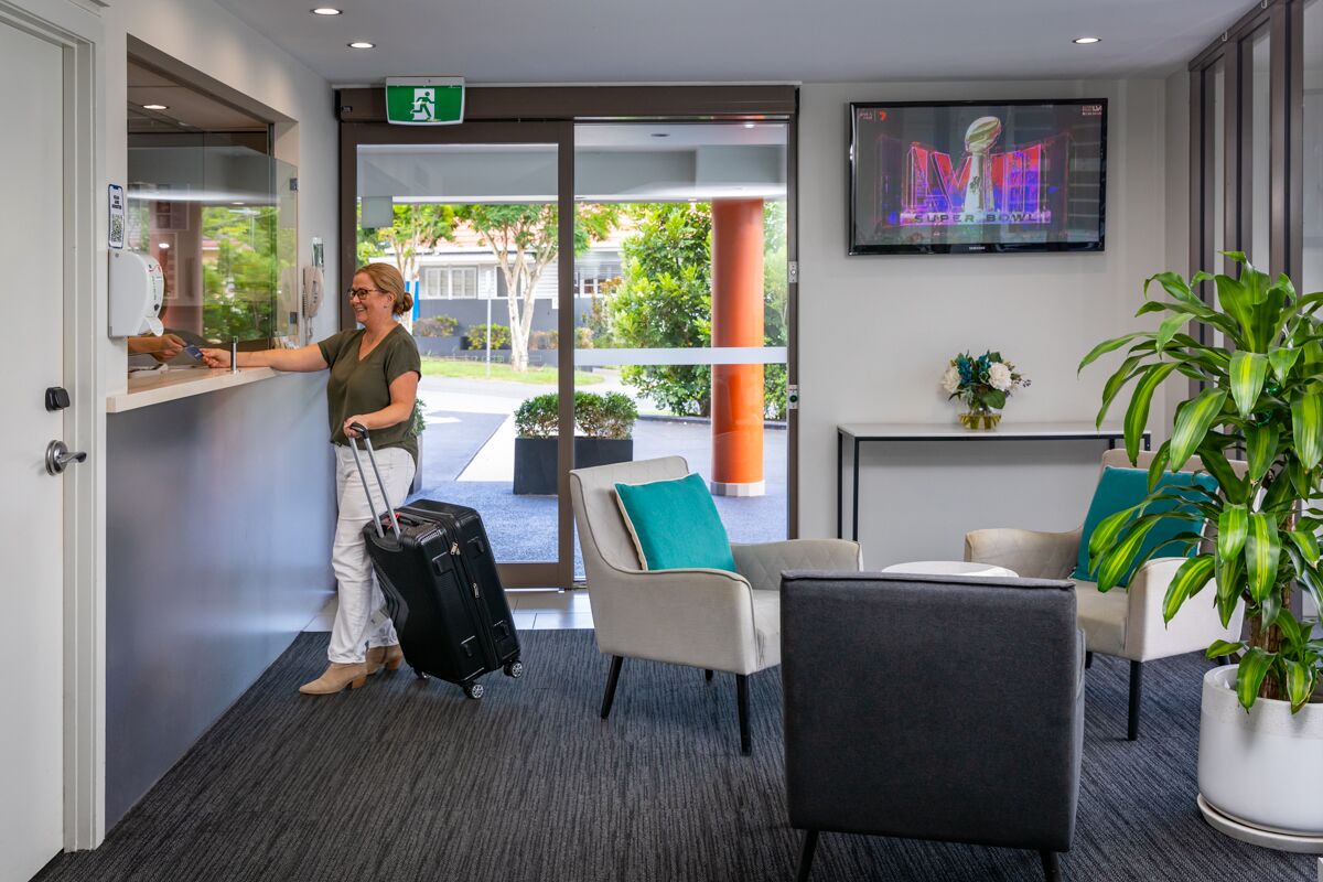 A reception area with a check-in counter, seating area, and a TV displaying the Super Bowl.
